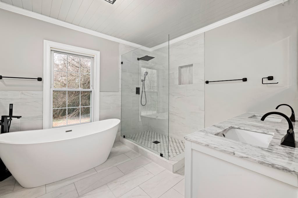 Sleek bathroom featuring a freestanding tub, glass shower, and marble accents.